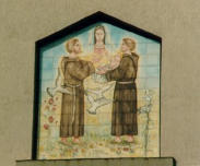 Inferiormente al frontone triangolare, inserita in una nicchia, è visibile l'immagine di due frati cappuccini in atto di venerare la Madonna con il Bambino in braccio (foto Tota)